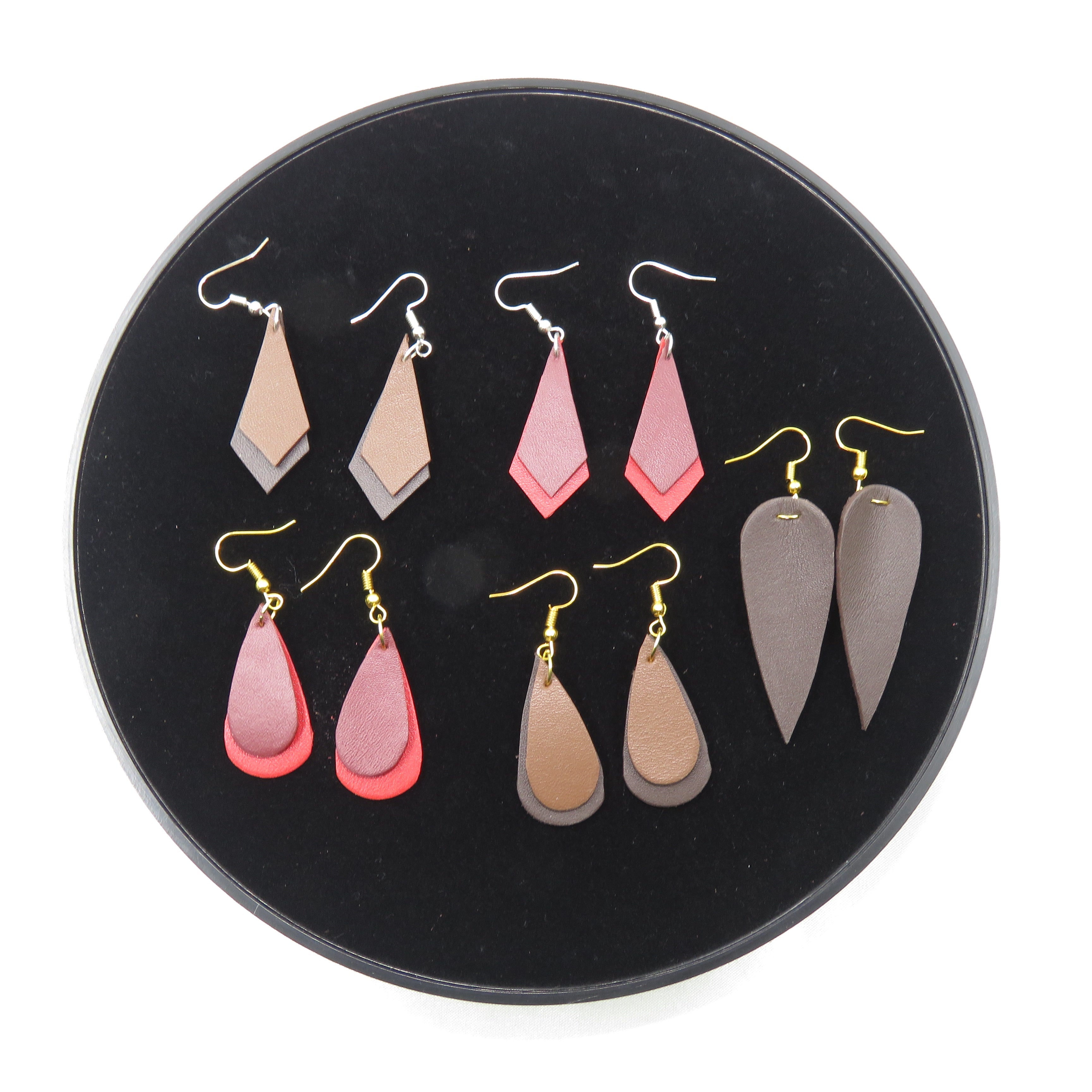 Set of earrings displayed on a black circular stand with a white background