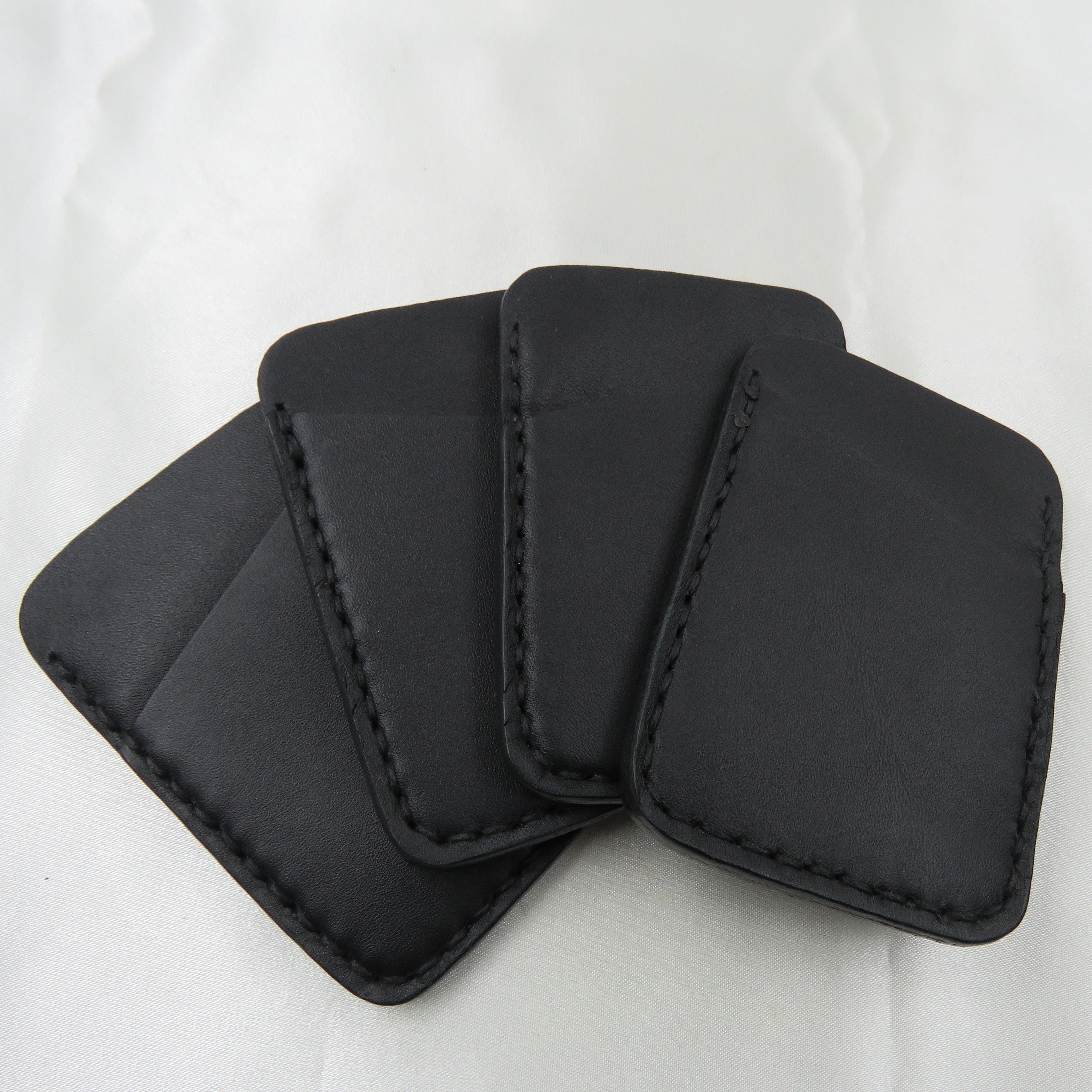 Four black leather card holders on a white background