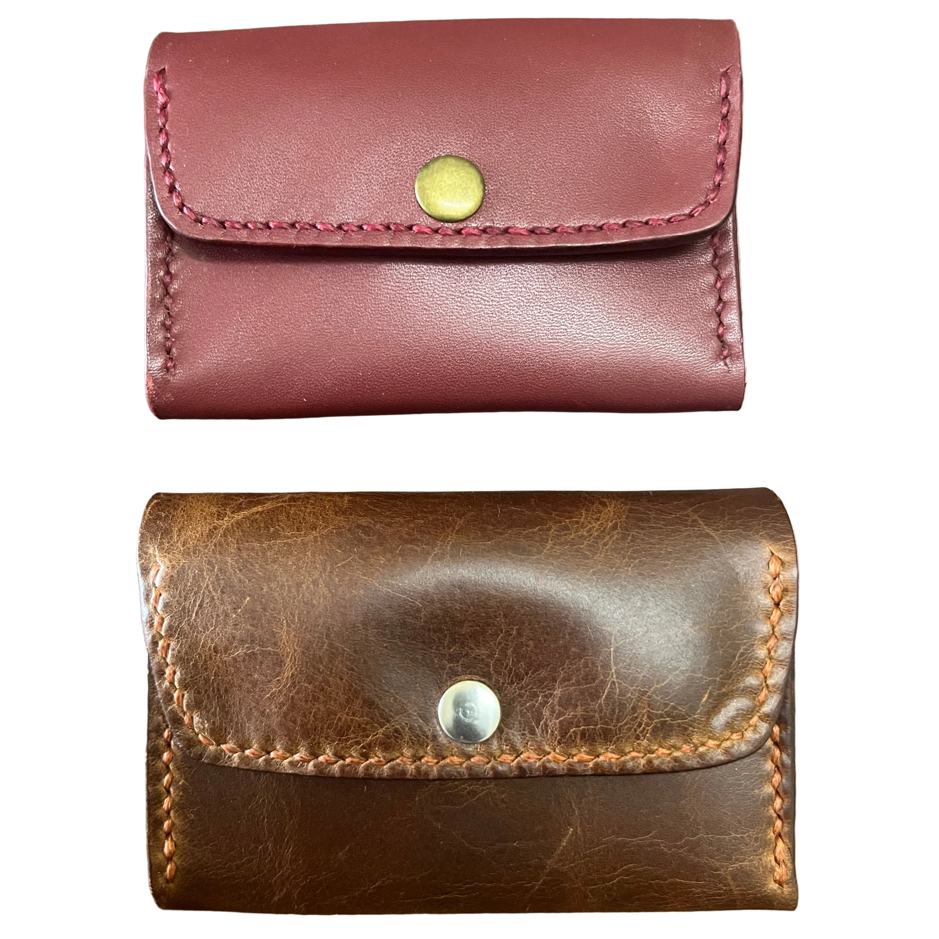 Two leather wallets, one red-brown and one brown, on a wooden surface.