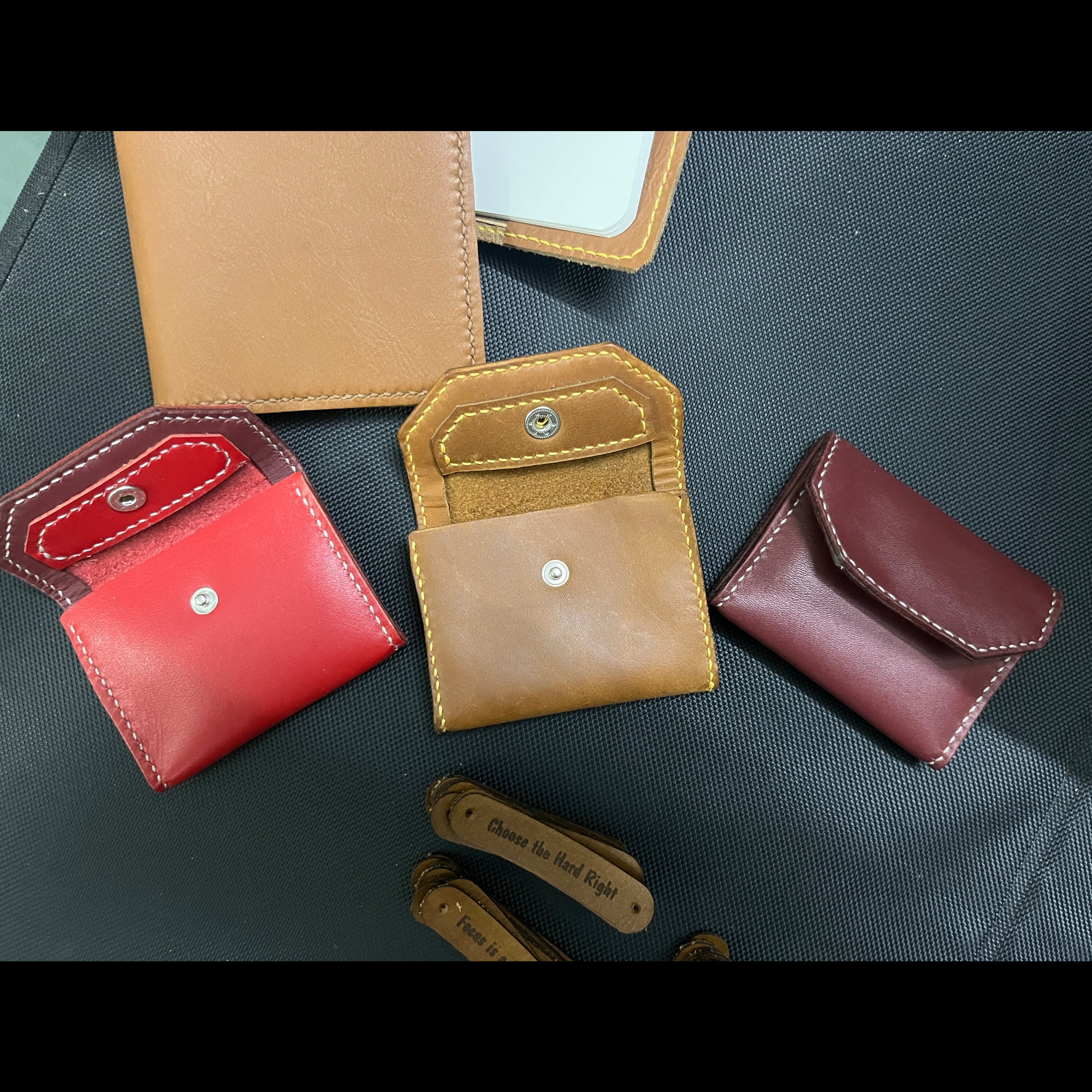 Collection of leather wallets in red, brown, and beige on a dark surface.
