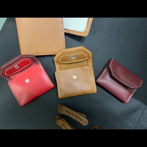 Collection of leather wallets in red, brown, and beige on a dark surface.