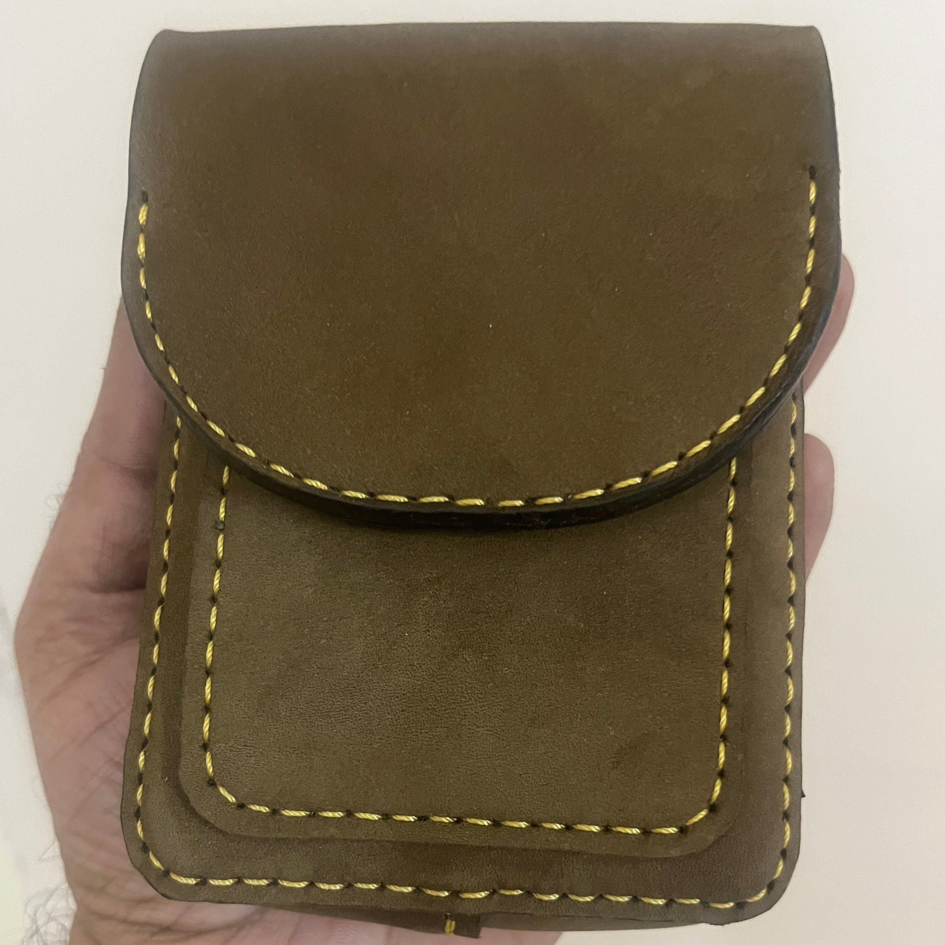 Brown leather pouch held in a hand with a plain background