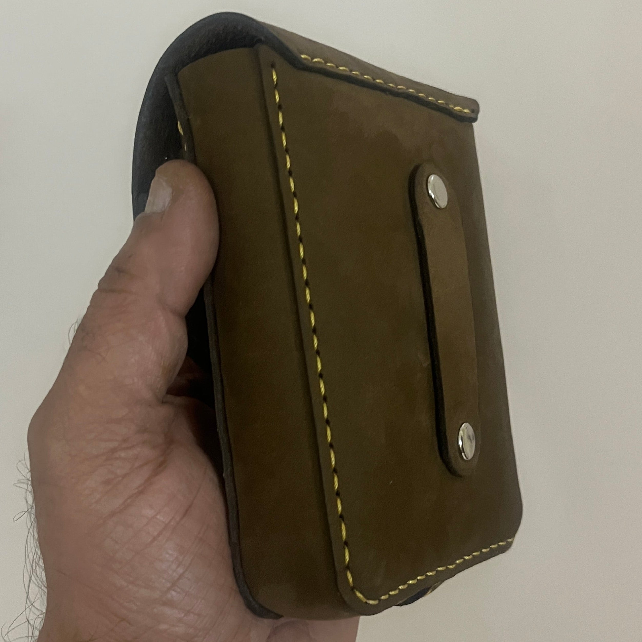 Hand holding a brown leather wallet against a plain background