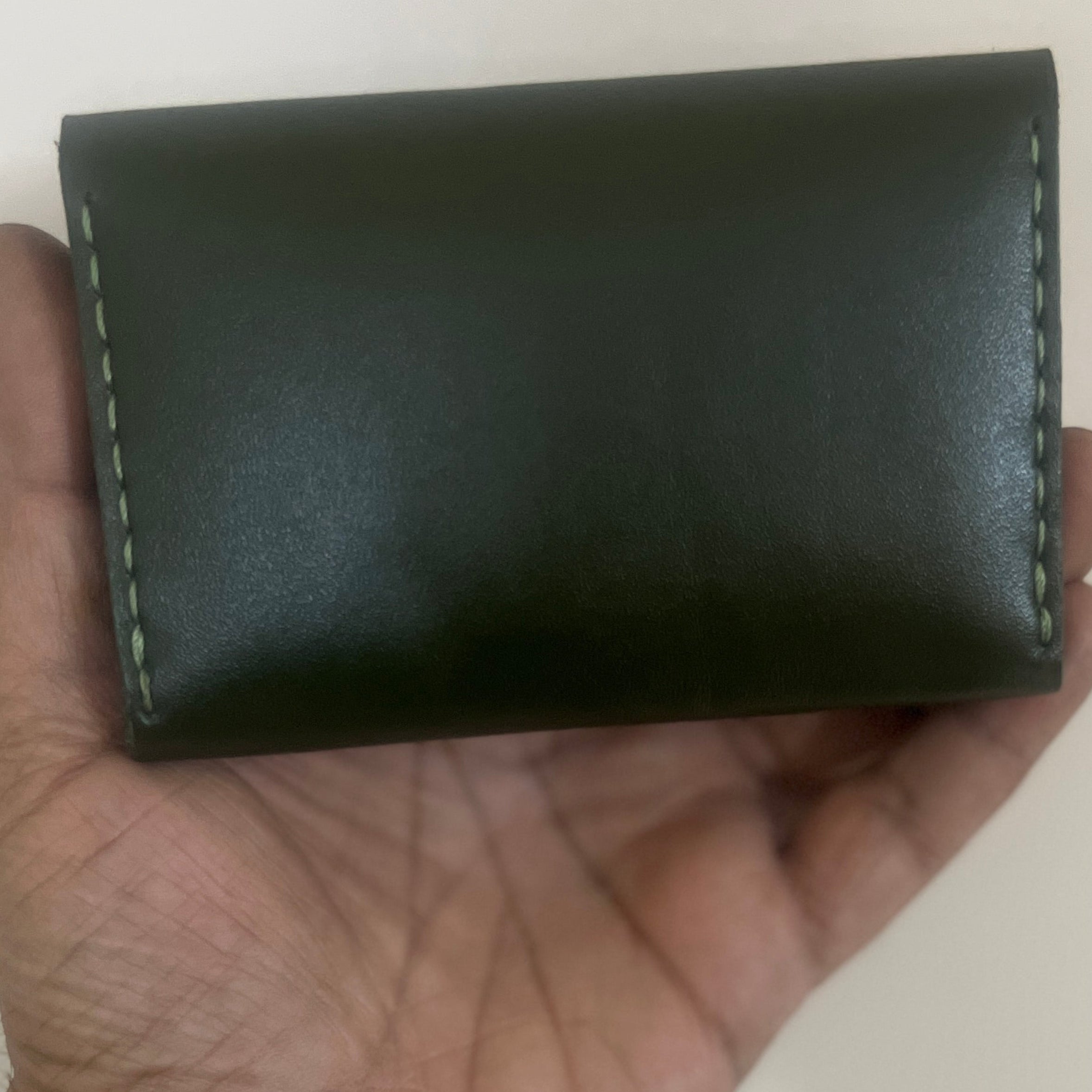 Hand holding a black leather wallet against a plain background