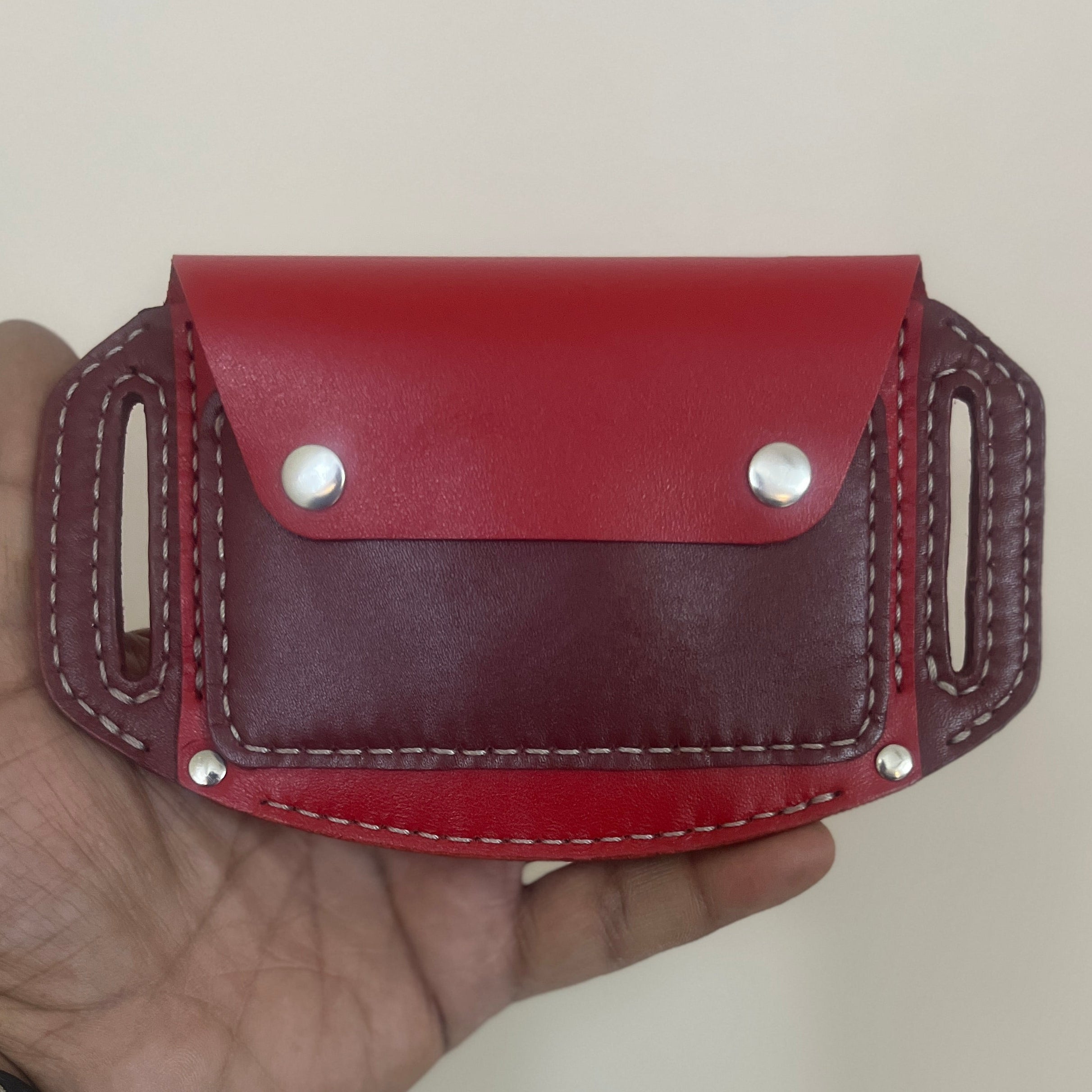 Red leather pouch held in a hand against a plain background