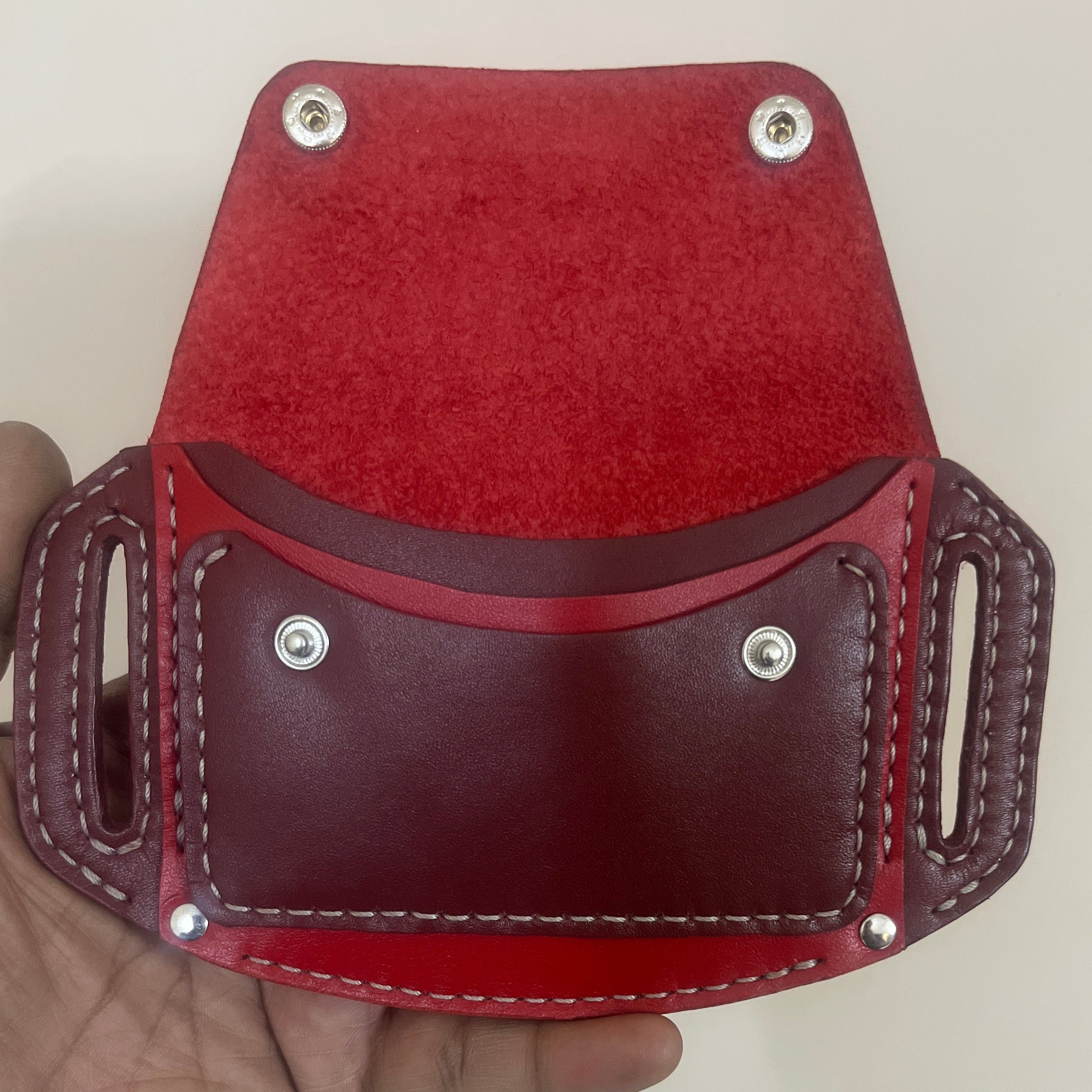 Red leather wallet held in a hand against a plain background