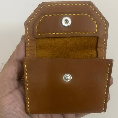 Brown leather pouch held in a hand against a plain background