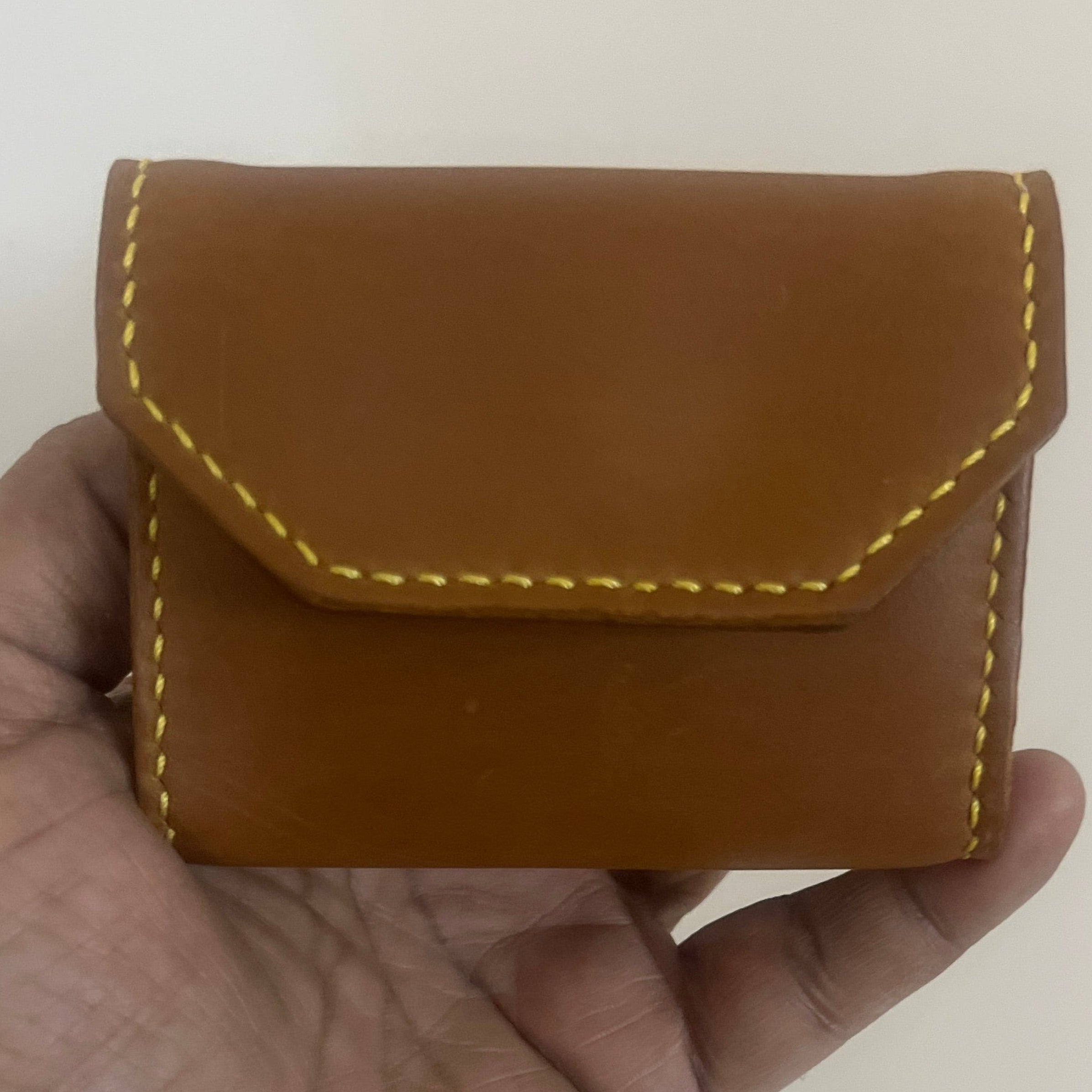 Hand holding a brown leather wallet against a plain background