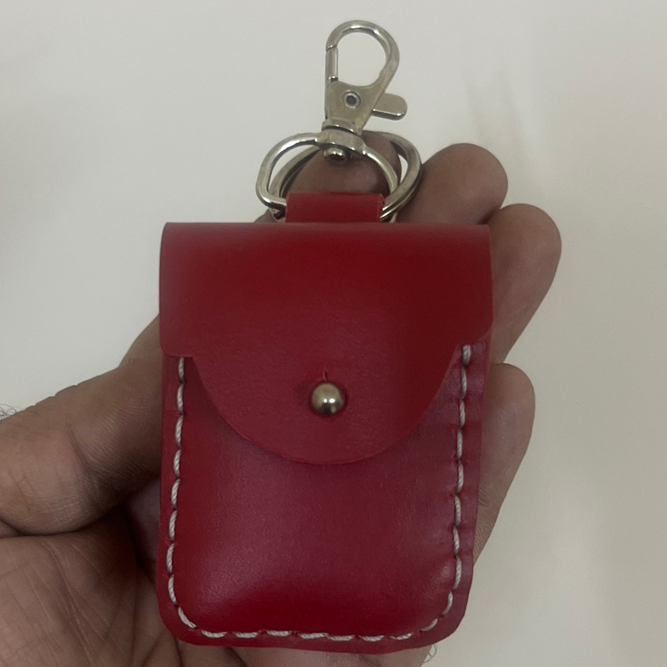 Red leather keychain holder held in a hand against a plain background