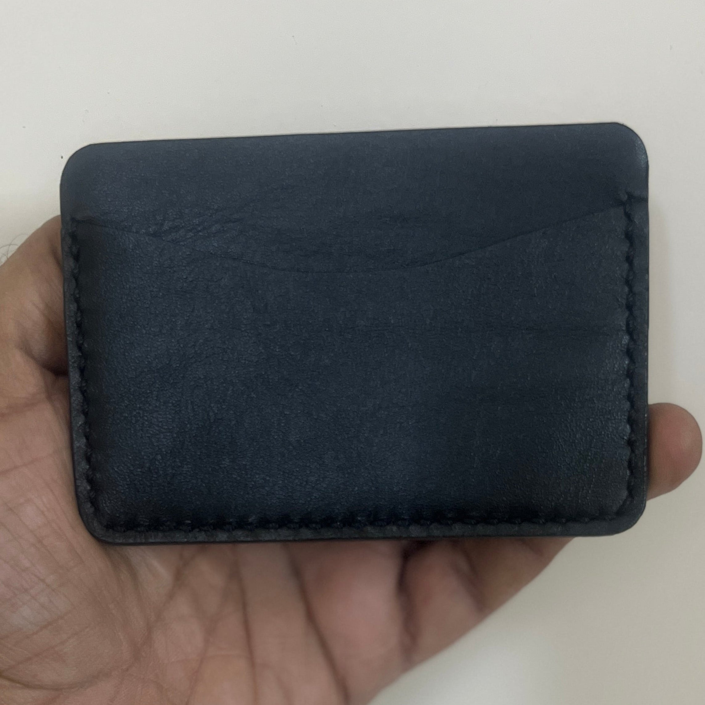 Hand holding a black leather wallet against a plain background
