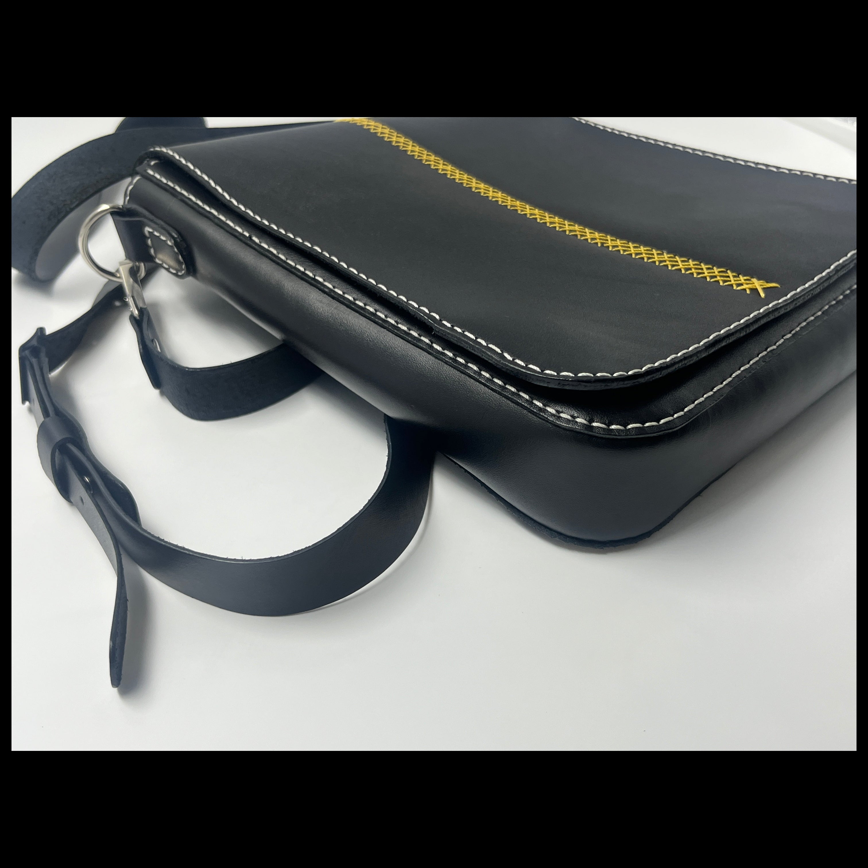 Black leather handbag with gold stitching on a white background