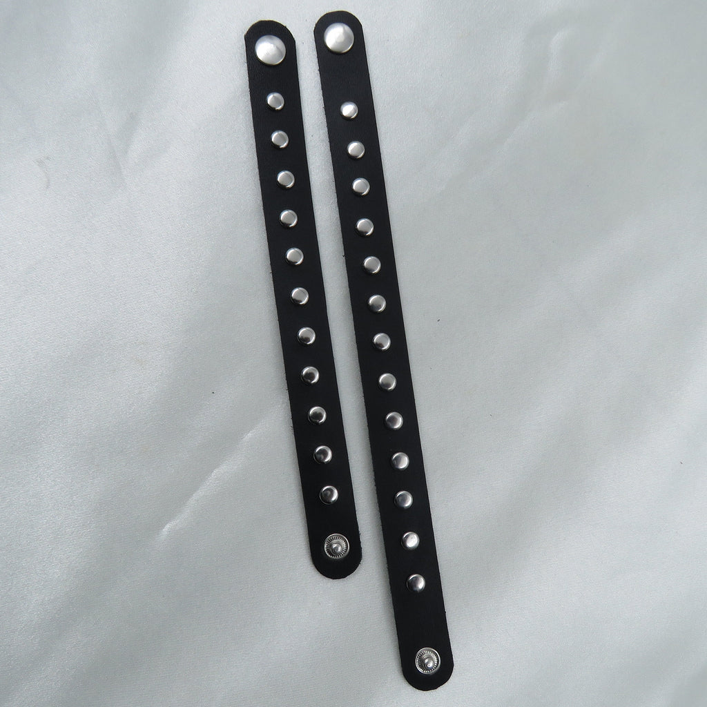 Two black leather straps with silver studs on a white background