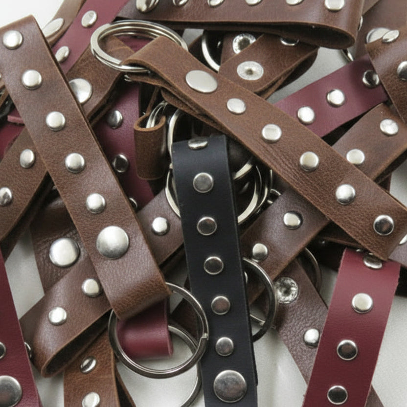 Collection of leather straps with studs and rings on a white background