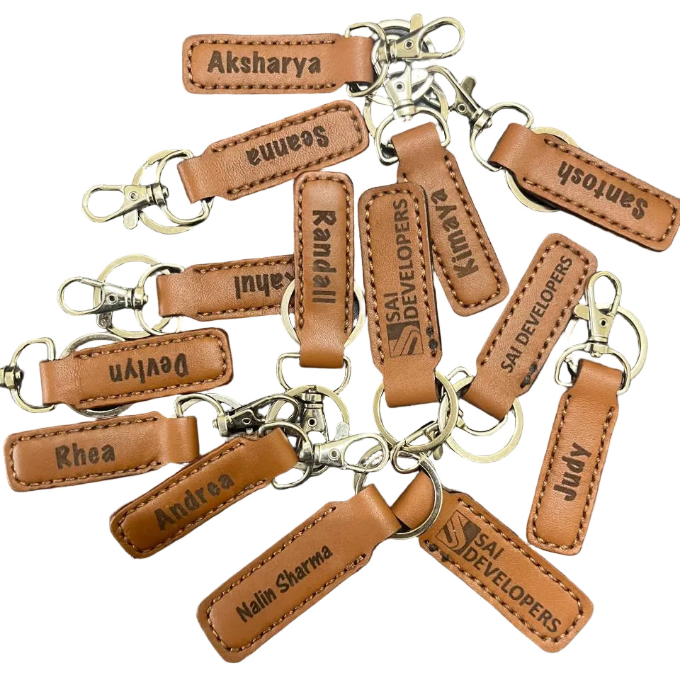 Collection of brown leather keychains with personalized text on a dark surface