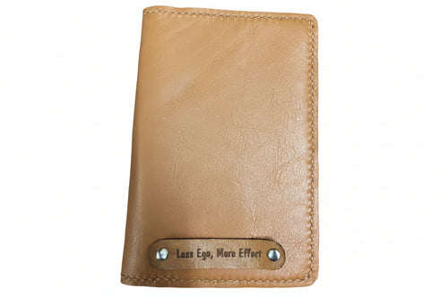 Brown leather wallet with 'Less Ego, More Effort' tag on a dark textured background