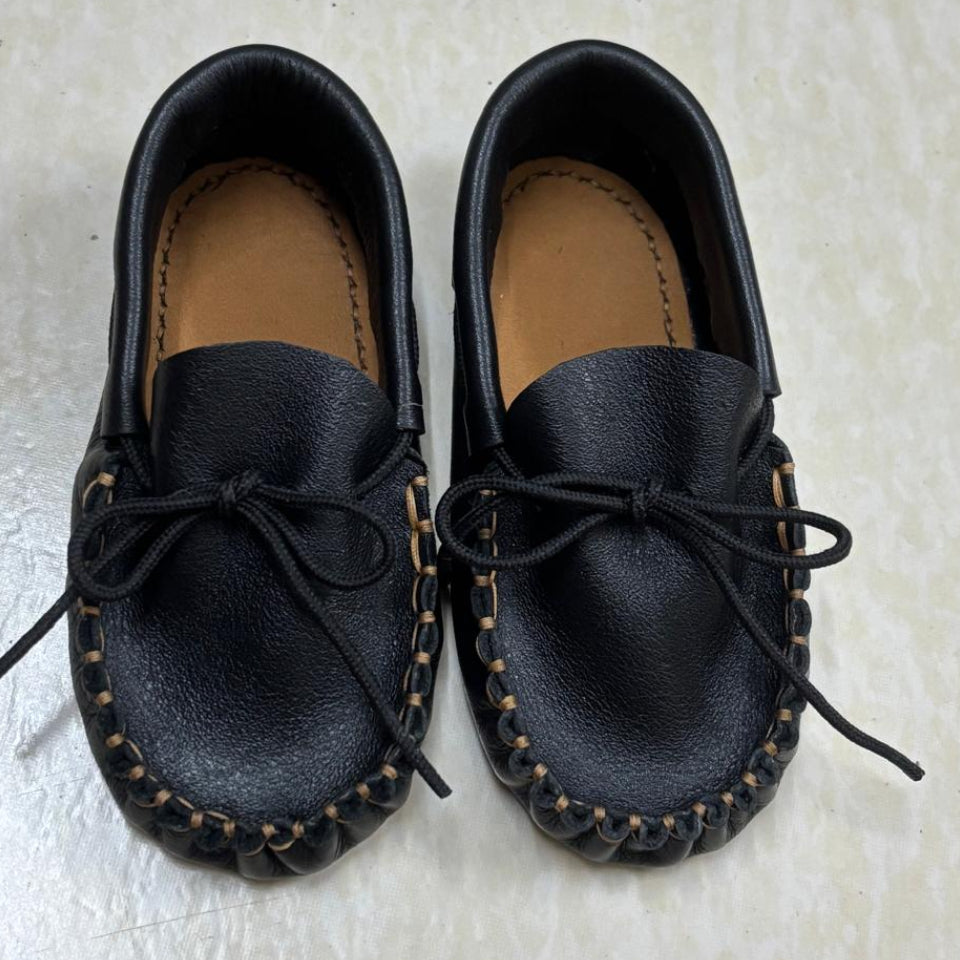 Pair of black leather moccasins on a light gray surface