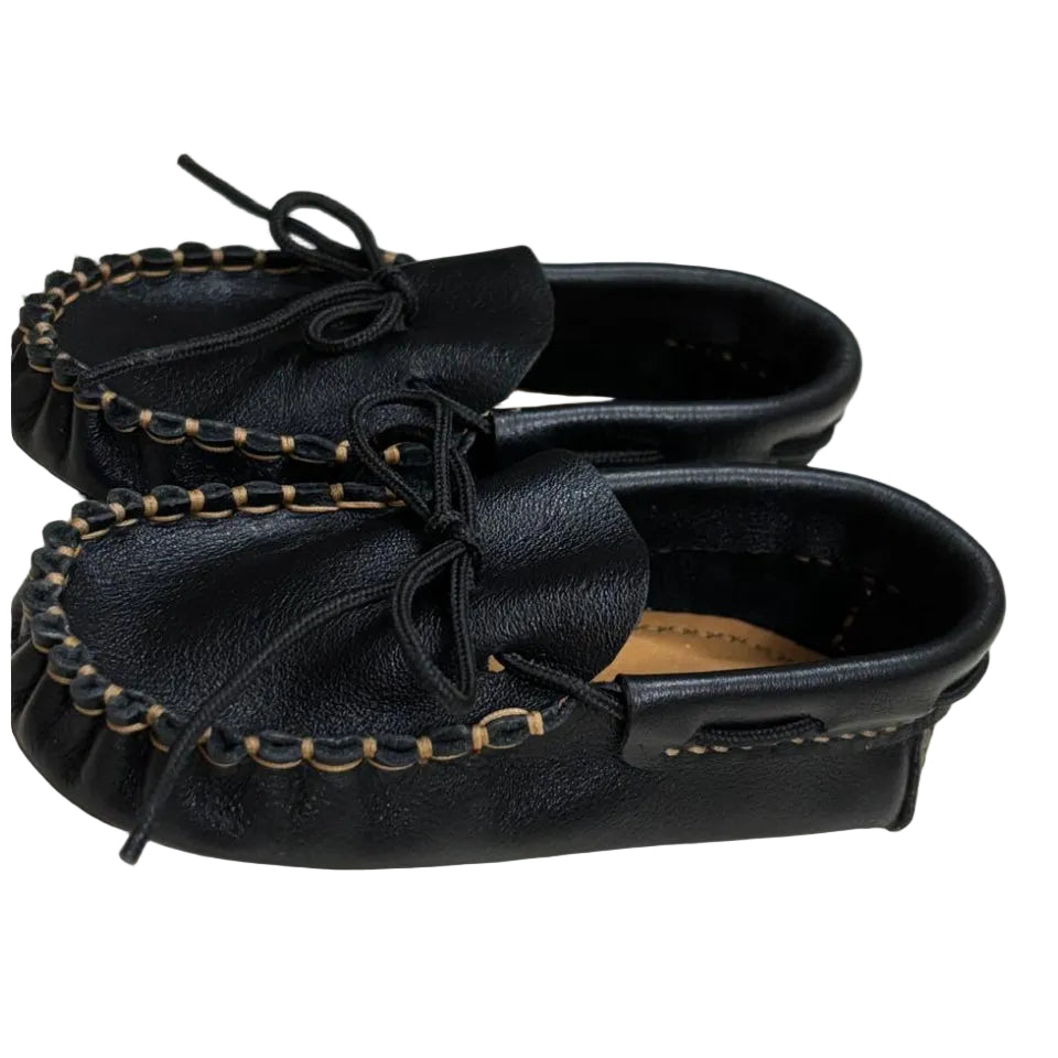 Pair of black leather moccasins with decorative laces on a light background