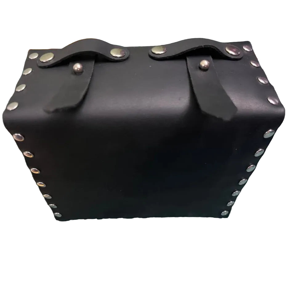 Black leather bag with studs on a green cutting mat